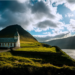 Church on a hillside next to a body of water on a cloudy day