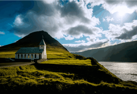 Church on a hillside next to a body of water on a cloudy day