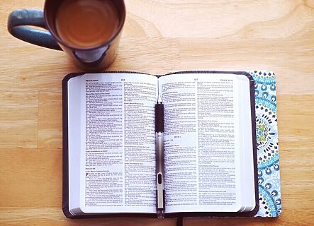 Bible on wooden table with cup of coffee