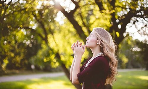Woman praying near trees
