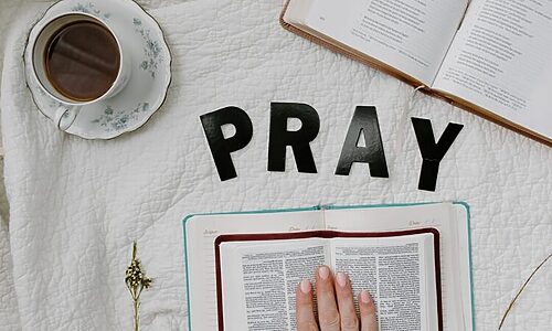 Word Pray spelled out, two Bibles, and a cup of tea