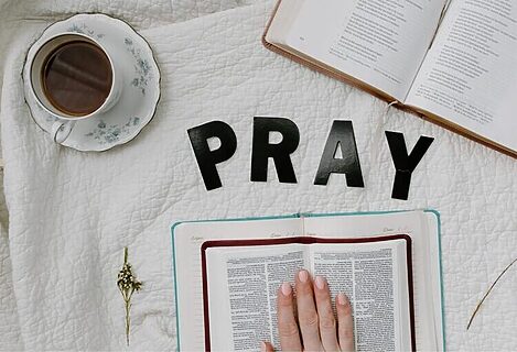 Word Pray spelled out, two Bibles, and a cup of tea