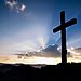 Cross on a hill with sunrise covered by clouds