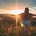 Woman with arms outstretched standing in field at sunrise