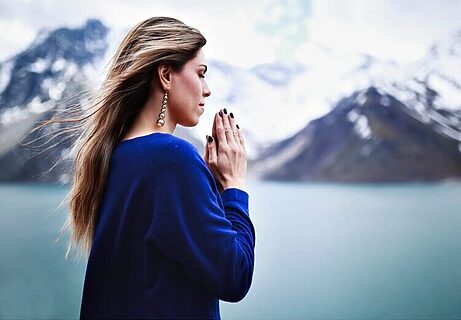 Woman praying to jumpstart faith in front of mountain