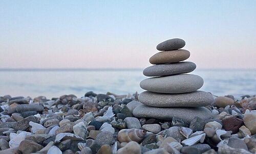 stack of rocks by body of water as analogy for strengthening faith
