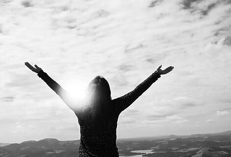 Black and white phot of woman with hands and looking at sky illustrate victory in prayer