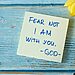 Tulips, pen, and sticky note saying “fear not I am with you God” on a table illustrate hearing God in season of chaos