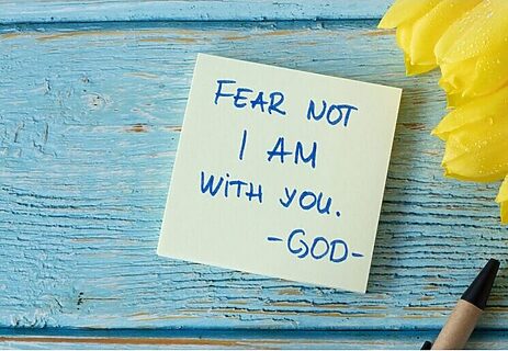 Tulips, pen, and sticky note saying “fear not I am with you God” on a table illustrate hearing God in season of chaos