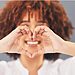 Woman smiling and forming heart with hands represents loving self because designed for God’s calling