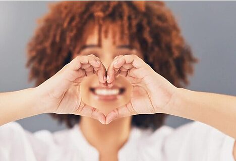 Woman smiling and forming heart with hands represents loving self because designed for God’s calling