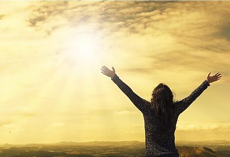 Woman raising hands to sun in sky illustrate discerning and hearing God’s voice