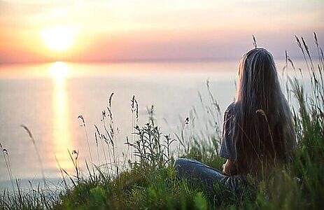 Picture of woman sitting by lakefront as part of hearing God’s voice by cultivating peace