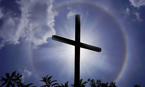 Cross with halo around it under a dark sky