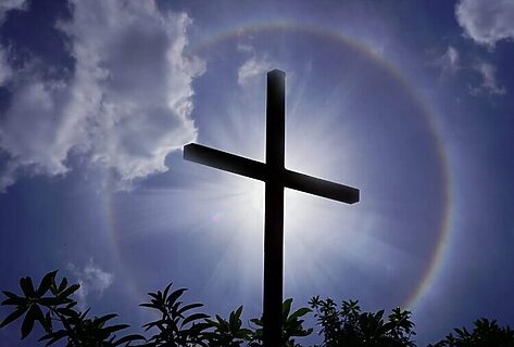 Cross with halo around it under a dark sky