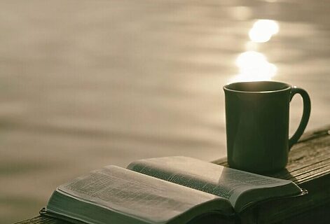 Bible and coffee mug by lakeside illustrate reading Bible