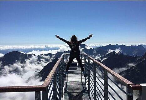 Woman staring over mountain top with hands raised illustrate passion for calling