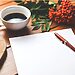 Desk with flowers, coffee cup, blank paper, and pen represent God writing your story