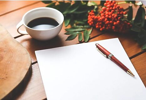 Desk with flowers, coffee cup, blank paper, and pen represent God writing your story