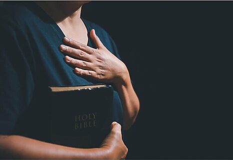 Woman with hand over heard and holding Bible to her chest represent knowing God is writing your story