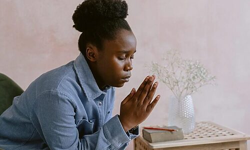 Woman praying near Bible illustrates submitting to God through prayer