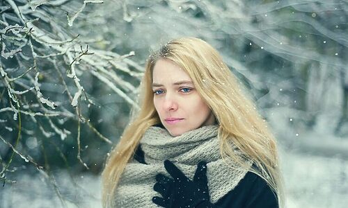 Woman outside on wintry day with scarf and gloves looking gloomy represent Christmas being hard or blue Christmas