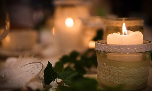 White candles on table with greenery illustrate finding God’s peace during stressful Christmas season