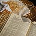 Open Bible, straw, blanket, and burlap with shadow of cross allude to true purpose of Christmas