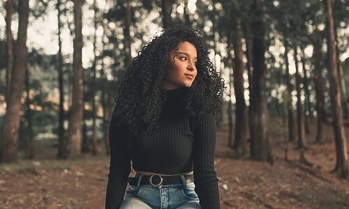 Woman in woods staring off with soft smile illustrates being content