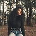 Woman in woods staring off with soft smile illustrates being content