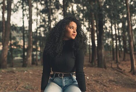 Woman in woods staring off with soft smile illustrates being content