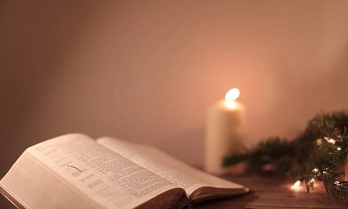 Bible opened to book of Psalms next to candle and greenery illustrate Bible verses about contentment