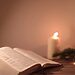 Bible opened to book of Psalms next to candle and greenery illustrate Bible verses about contentment