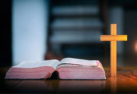 Wooden cross and open Bible on table illustrate reading gratitude Bible verses