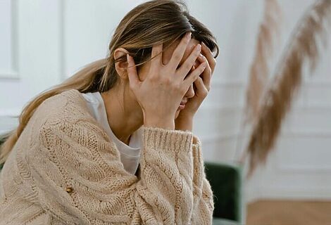 Picture of woman holding her head in her hands illustrates doubting God 