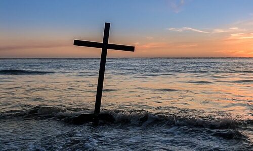 Cross planted near ocean represents being brought near through the blood of Christ