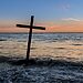 Cross planted near ocean represents being brought near through the blood of Christ