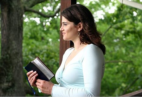 Image of woman holding Bible while standing on porch