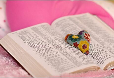 Image of Bible laying open and heart trinket sitting in the center illustrate God’s love through the Bible