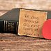 Scripture verse 1 John 4:19 next to Bible and heart represents God’s love for us