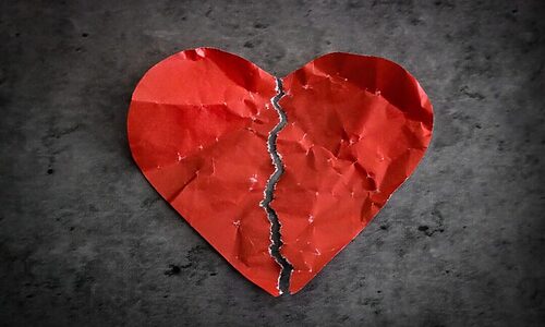 Red paper heart ripped in two represents feeling unloved