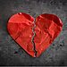 Red paper heart ripped in two represents feeling unloved