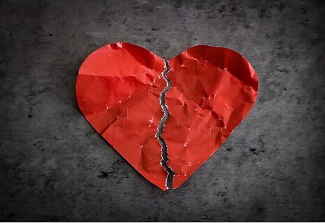 Red paper heart ripped in two represents feeling unloved